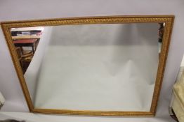 A LARGE RECTANGULAR GILT FRAMED WALL MIRROR, 20TH CENTURY, with gadroon and leaf design frame.