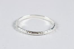 A HEAVY SILVER HAMMERED BANGLE.