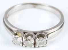 A WHITE METAL AND DIAMOND THREE STONE RING.