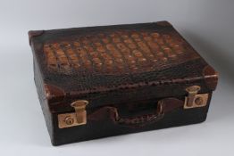 A GOOD EARLY 20TH CENTURY CROCODILE SKIN SUITCASE, with a pair of brass locks/catches and green