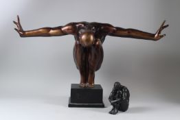 A LARGE BRONZE PATINATED CAST METAL FIGURE, of a crouching man, arms outswept, on an ebonised