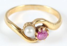 A YELLOW METAL, RUBY AND PEARL CROSSOVER RING.