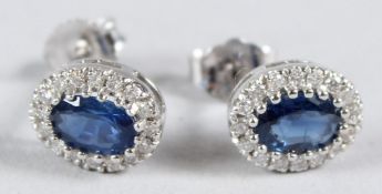 A PAIR OF 18CT WHITE GOLD, SAPPHIRE AND DIAMOND OVAL CLUSTER EAR STUDS.