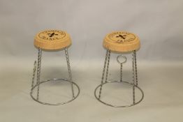 A PAIR OF NOVELTY CORK AND CHROME PLATED CHAMPAGNE ENCLOSURE STYLE STOOLS. 52cms high.