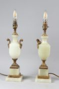 A PAIR OF ONYX AND ORMOLU URN SHAPED TABLE LAMPS, on square bases. 40cms high.
