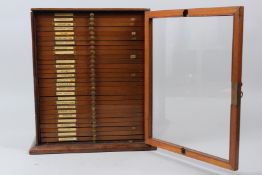 A MAHOGANY TABLE TOP SINGLE DOOR CABINET, containing 28 drawers of microscope slides.