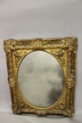 A LARGE DECORATIVE GILT FRAMED RECTANGULAR WALL MIRROR, the oval mirror plate with a frame decorated
