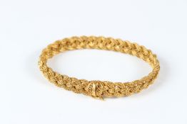 A YELLOW METAL WOVEN BRACELET.