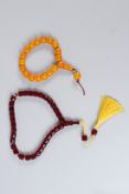 A STRING OF CHERRY AMBER STYLE BEADS, and a string of egg yolk style beads.