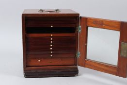 A SMALL MAHOGANY SINGLE DOOR TABLE TOP CABINET, containing 11 drawers of microscope slides.