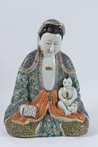 A CHINESE PORCELAIN STATUE OF GUANYIN holding a baby and a calligraphy tablet, with famille rose