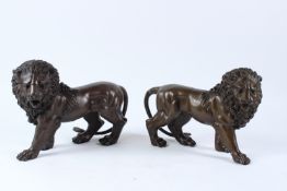 A PAIR OF BRONZE MODELS OF STANDING LIONS. 30cms long.