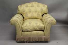 PARKER & FARR, A LARGE ARMCHAIR, upholstered in a yellow ground floral fabric with tassel fringe.
