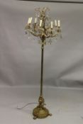 A HIGHLY ORNATE BRASS FLOOR STANDING LAMP, with eight scrolling branches hung with cut glass pear