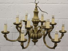 AN ORNATE BRASS CHANDELIER, with six scrolling branches, each with two light fittings. 84cms