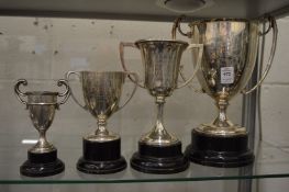 A collection of four silver twin handled trophy cups on pedestal bases.