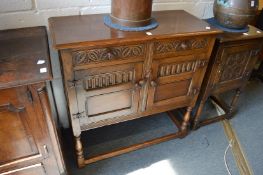 A reproduction oak small sideboard with two frieze drawers and two cupboard doors on turned