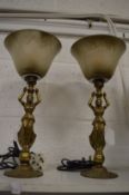 A pair of cast brass figural uplighter style table lamps with opaque glass shades.