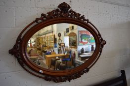 A Victorian mahogany oval wall mirror with ornately carved frame.