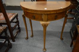 A walnut demi-lune fold-over tea table with two drawers.