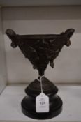 A bronze pedestal cup on a marble base.