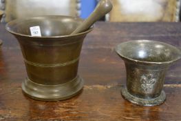 A large bronze pestle and mortar and another mortar.