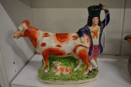 A Staffordshire pottery cow creamer modelled as a cow, calf and farmhand.