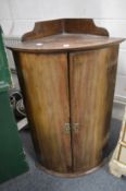 A mahogany bow fronted hanging corner cabinet.