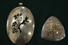 Two silver floral decorated brooches.