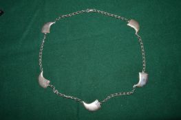 A silver necklace with claw shaped mounts.