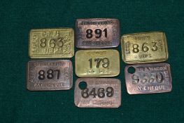 A group of stamped metal railway pay checks.