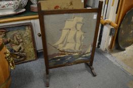 An oak framed wool work firescreen depicting a sailing ship.