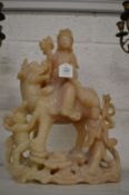 A Chinese carved soapstone group modelled as guan yin seated on the back of a temple lion with