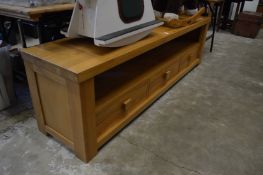 A large oak three drawer wide screen TV stand.