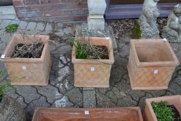 A set of three terracotta basket weave style square shaped planters.