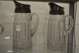 A pair of glass jugs with plated mounts.