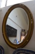 A gilt framed oval wall mirror.