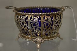 A pierced silver sugar basket with blue glass liner.