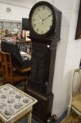 A longcase clock with carved oak case and circular dial.