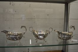 A pair of silver sauce boats together with a similar silver sugar bowl.
