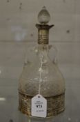 A silver mounted cut glass decanter with matching silver coaster base.