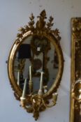 A pair of 19th century gilt framed oval three light girandoles.