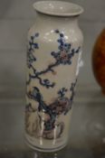 A Chinese cylindrical vase painted with a bird amongst trees.