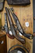 Three reproduction flintlock pistols.