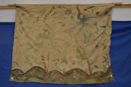 An embroidered wall hanging depicting birds amongst trees.