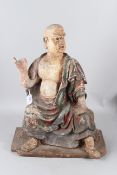 A CARVED WOOD AND POLYCHROME STATUE OF A SEATED MONK OF ARHAT, sitting cross legged. 28cms high.