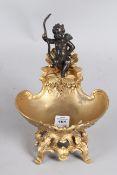 A BRONZE AND GILT BRONZE TABLE SALT, modelled as a cherub on a shell. 14cms wide.