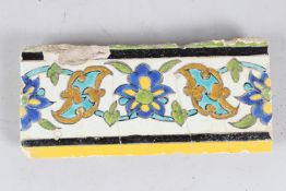 A 17TH CENTURY PERSIAN SAFAVID GLAZED POTTERY TILE. 24cms long.