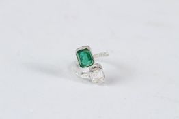 AN 18CT WHITE GOLD EMERALD AND BAGUETTE CUT DIAMOND CROSSOVER RING.