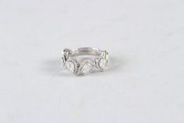 AN 18CT WHITE GOLD AND DIAMOND BAND RING, set with pear shaped and emerald cut centres, surrounded